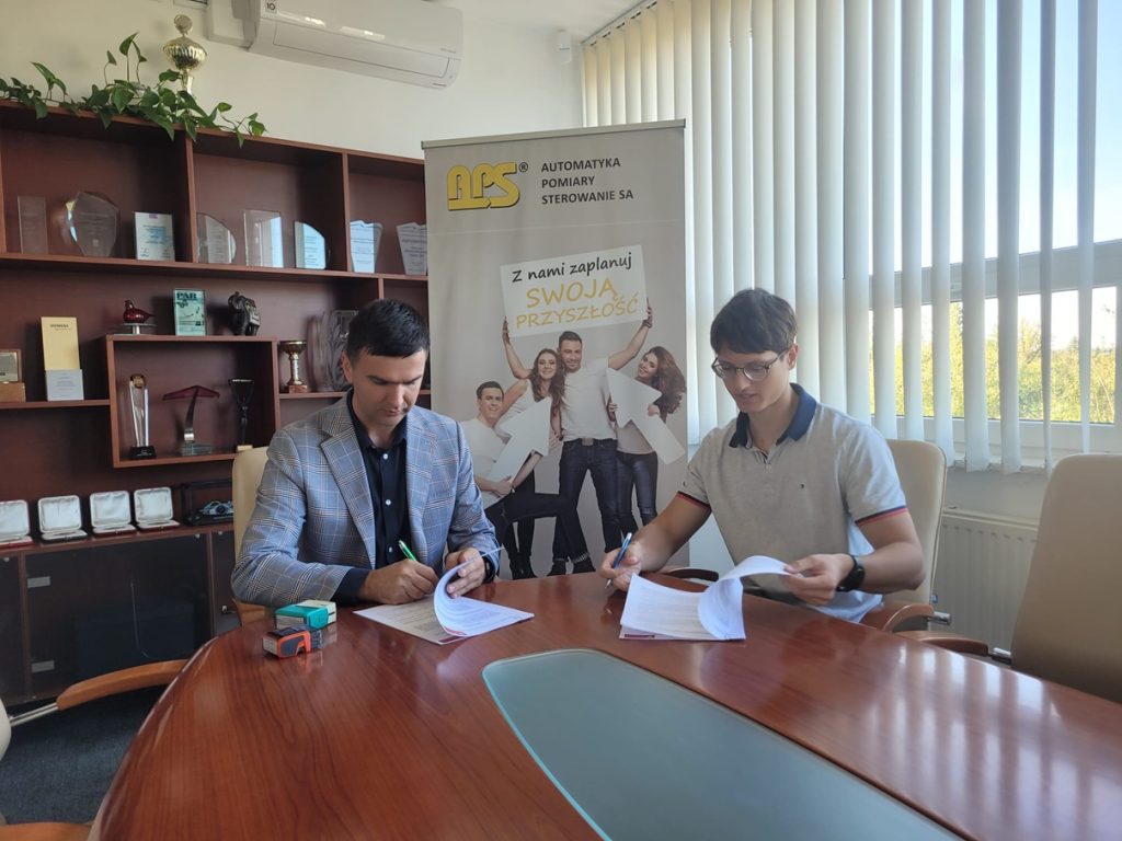 Prezes APS S.A. oraz student Wydziału Elektrycznego Politechniki Białostockiej podczas podpisywania umowy stypendialnej w sali narad zarządu.
